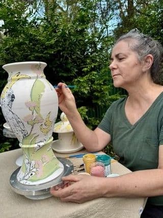 Christine Pickett painting underglaze onto a vase