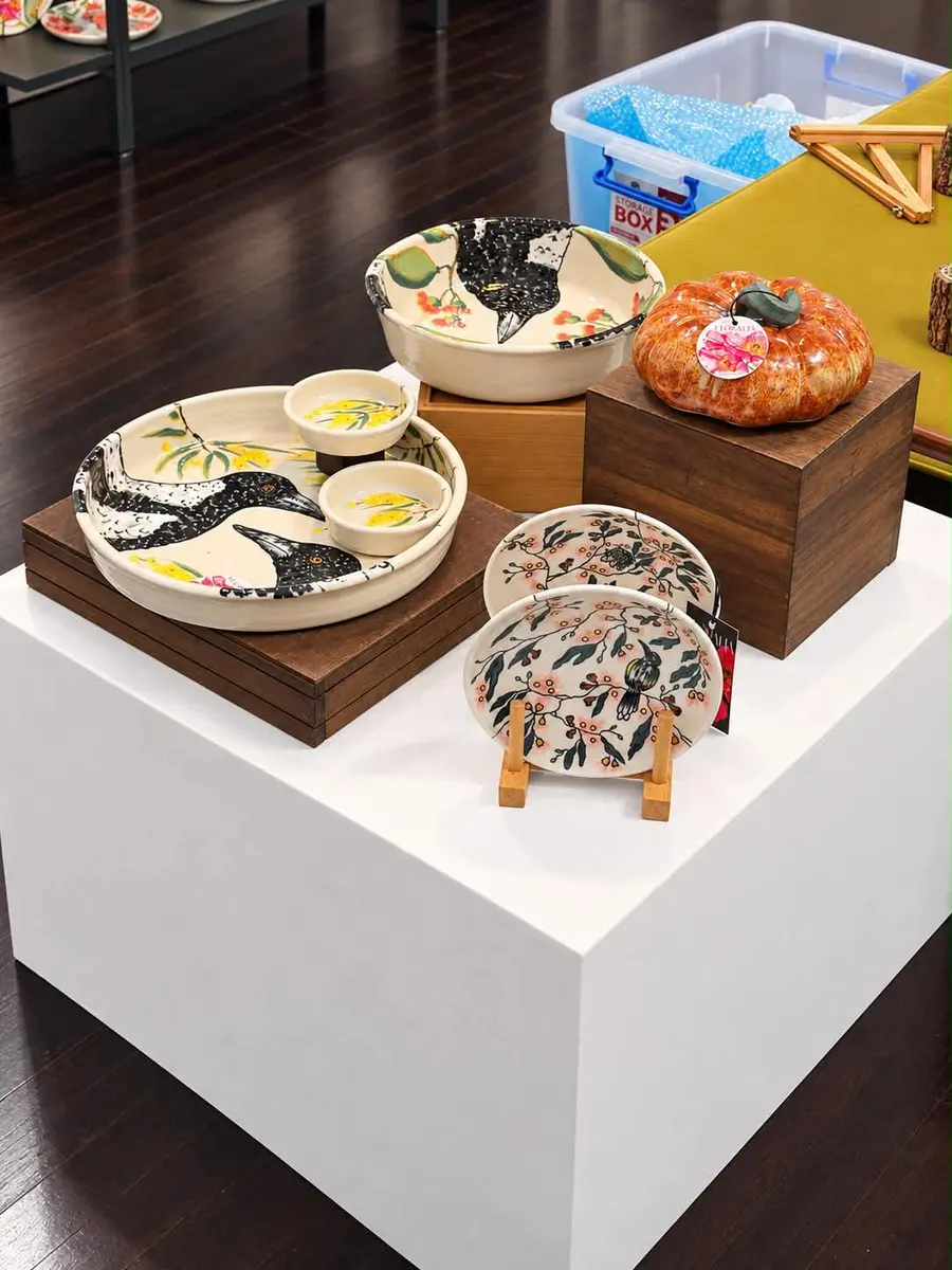 Hand-painted ceramic bowls and plates on a white plinth