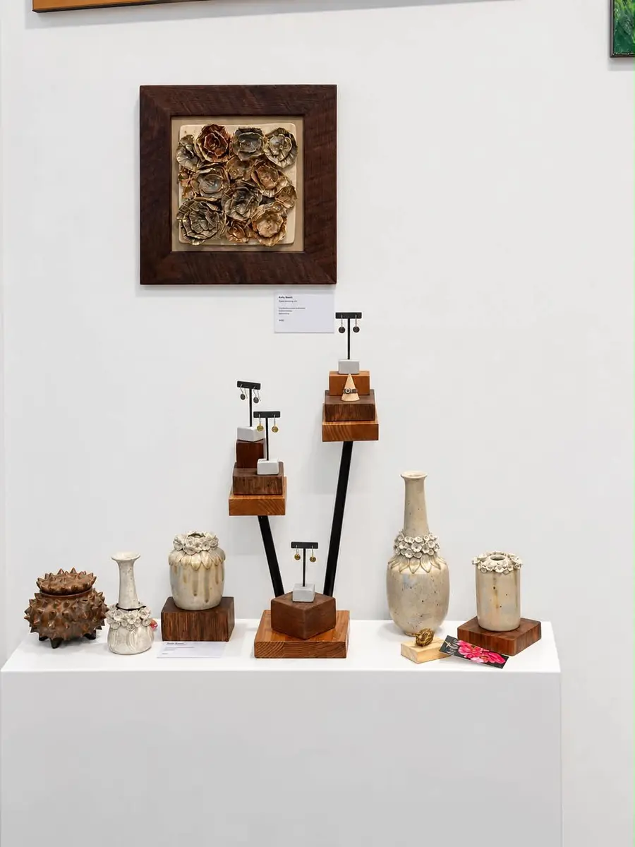 Carved ceramic wall tile above a plinth of vases and sculptural pieces