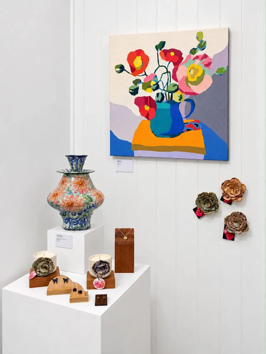 A floral painting beside a patterned vase on a plinth