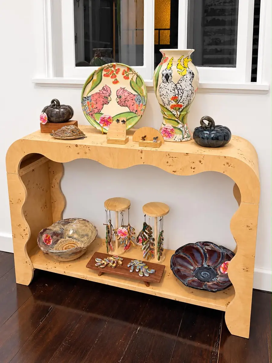 Hand-painted plates, vases and bowls on a curved timber console
