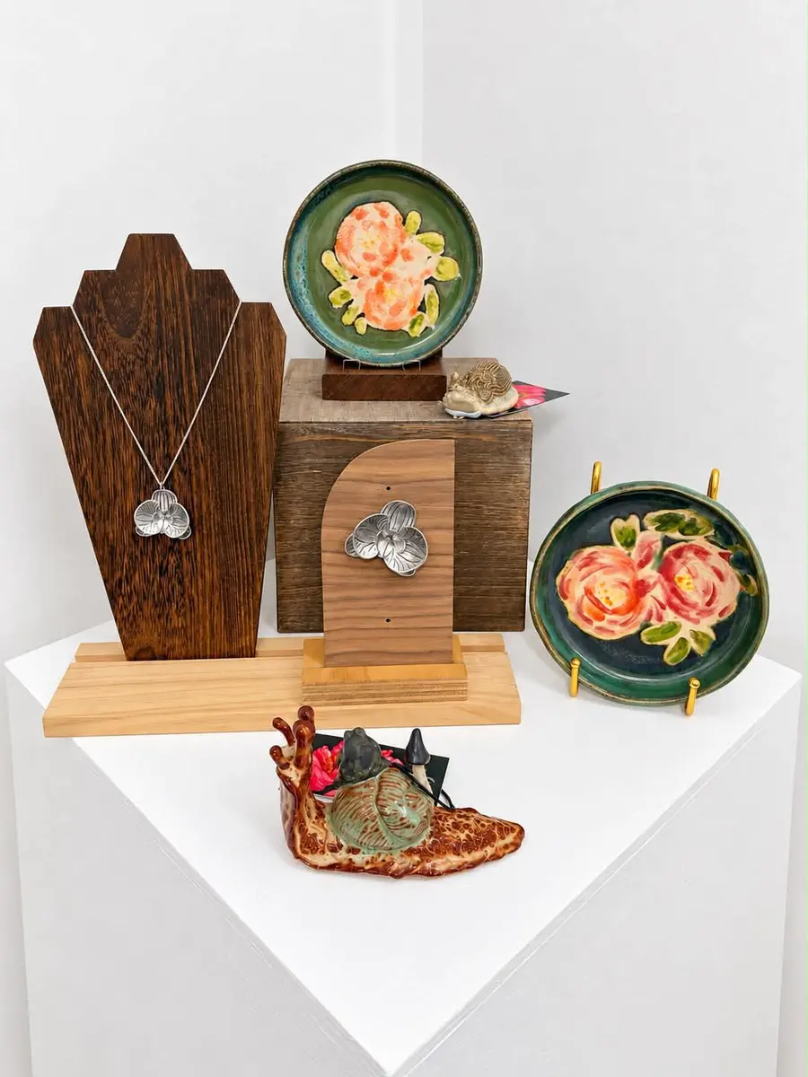 Pendant necklaces and painted ceramic dishes on a display stand