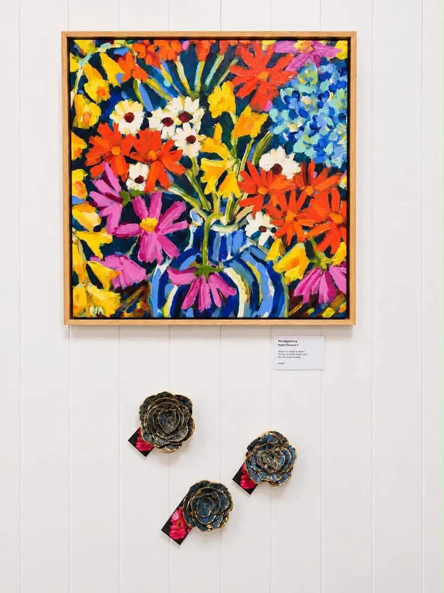 A vivid floral painting above small ceramic wall pieces