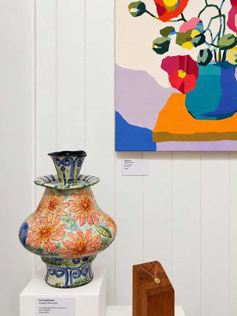 A large patterned vase beneath a colourful floral painting