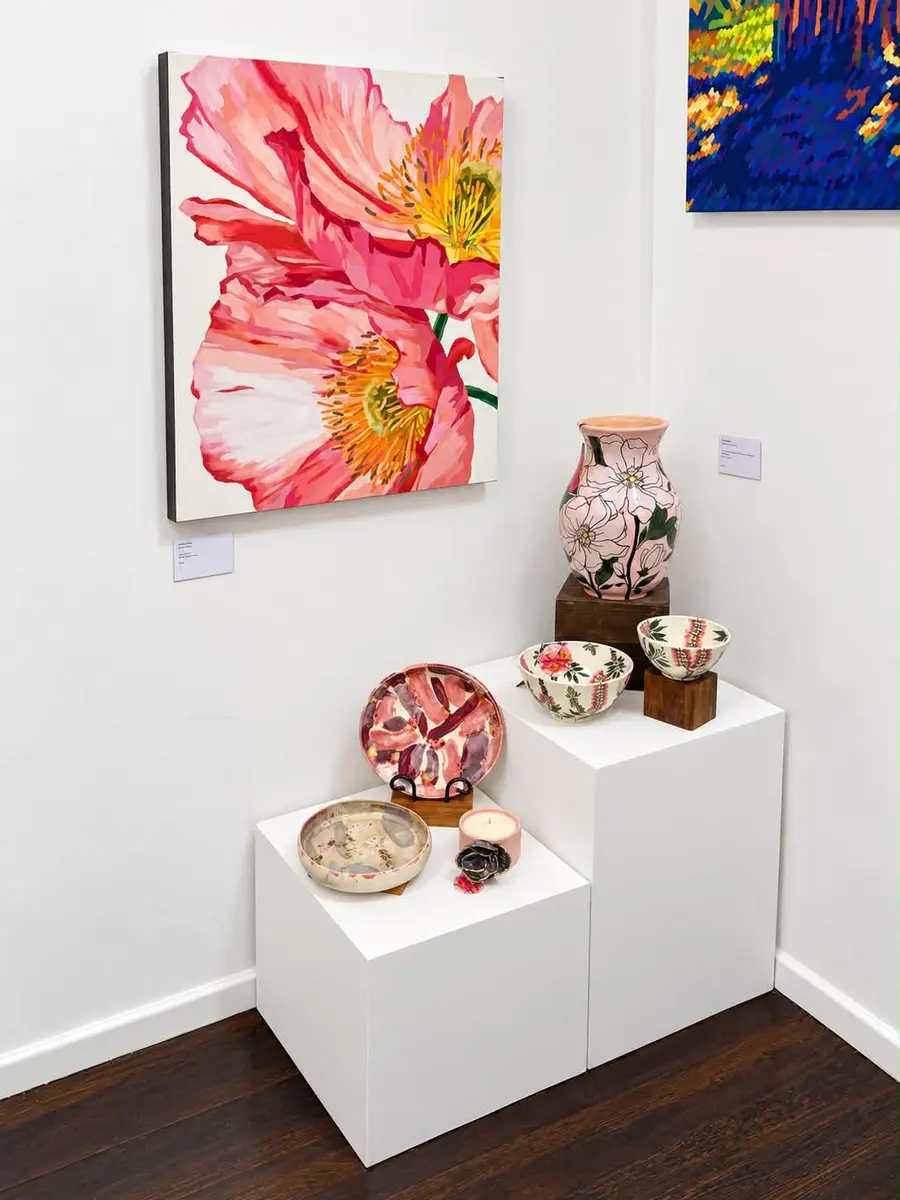 A pink poppy painting above ceramics on stepped plinths