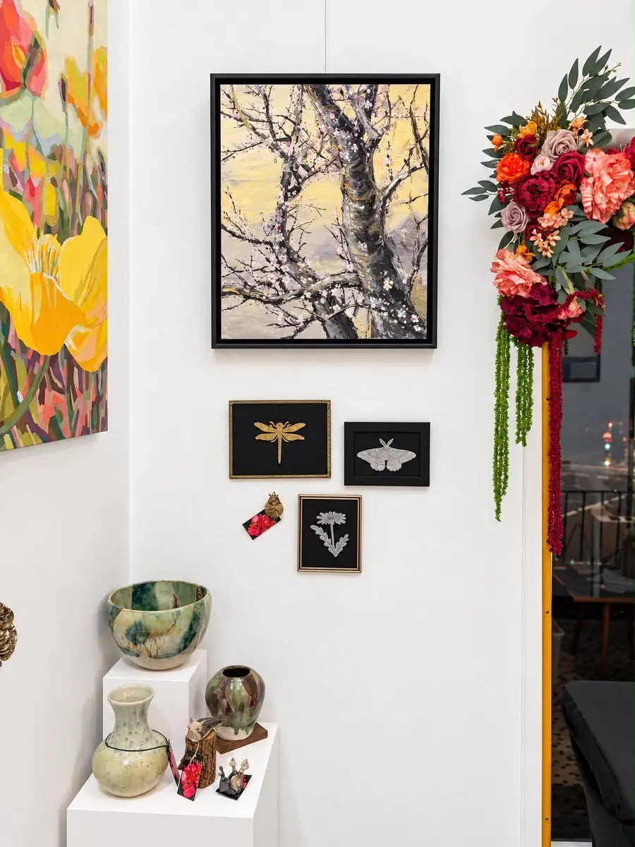 A bare-branch print and framed insects beside a flower arrangement