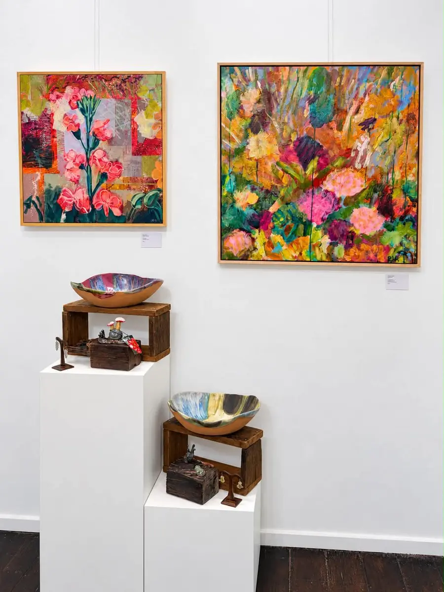 Two vibrant floral paintings above ceramics on plinths